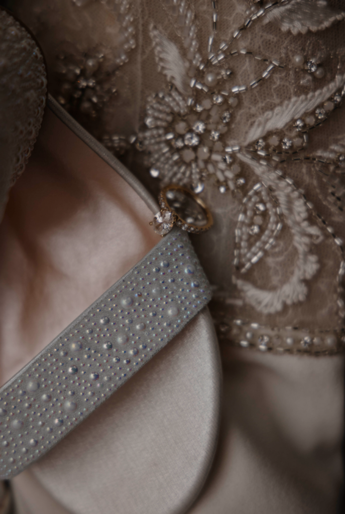 Bridal detail photo of wedding shoes, rings, and dress fabric