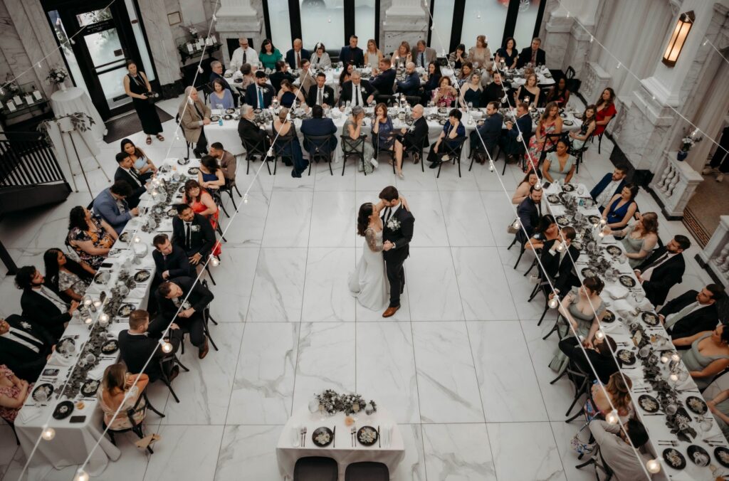 Bride and groom sharing a romantic dance surrounded by friends and family