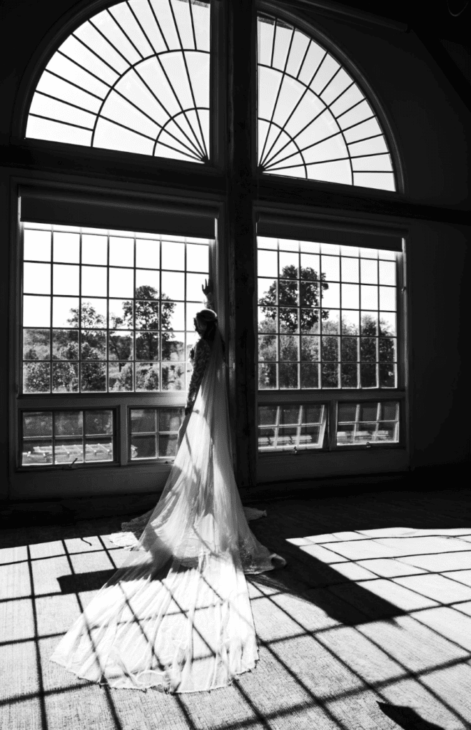 Editorial photo of bride looking out window on wedding day