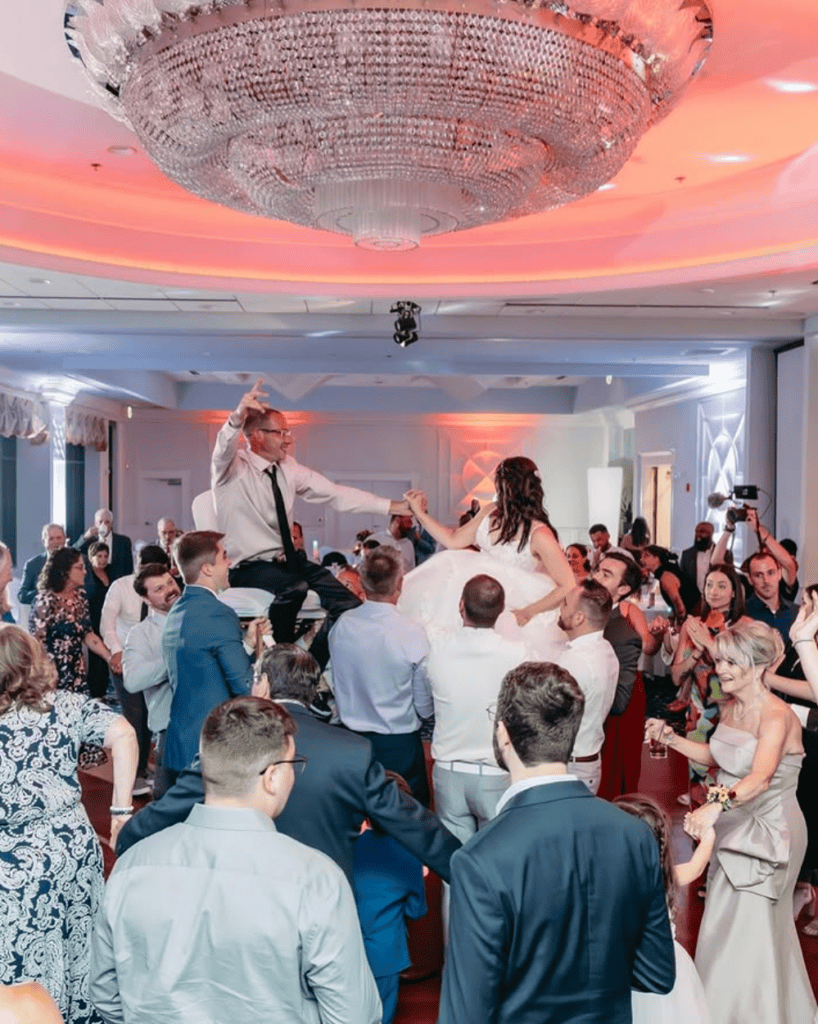 Bride and groom lifted by friends and family on the wedding dance floor