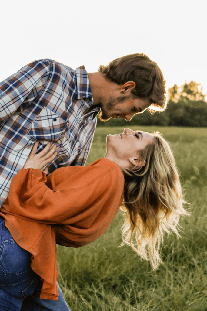 couple dipping in a field for engagement photos