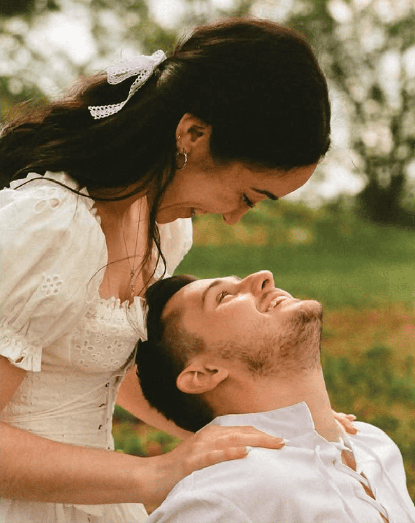 couple looking at each other in a field during their engagement photoshoot