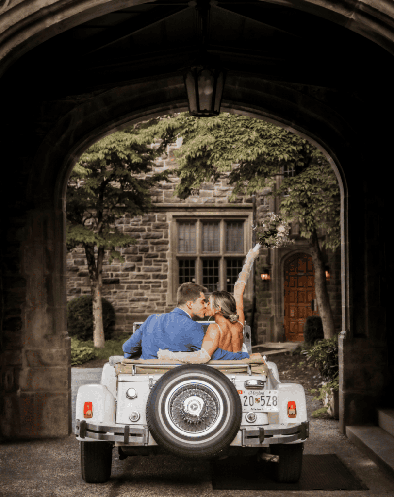 Bride and groom sharing a romantic kiss inside a car, with the bride holding her wedding bouquet.