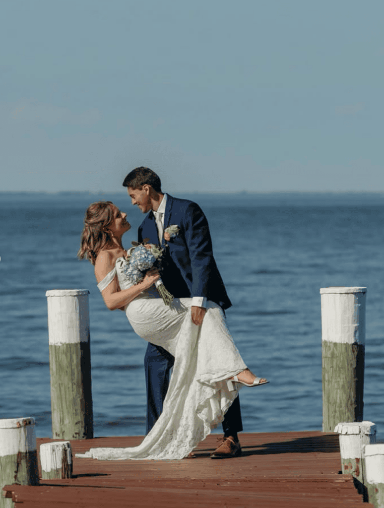 groom dips bride on waterfront pier