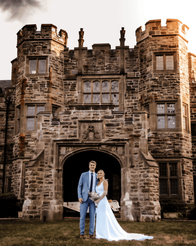 bride and groom posing in front of castle on wedding day