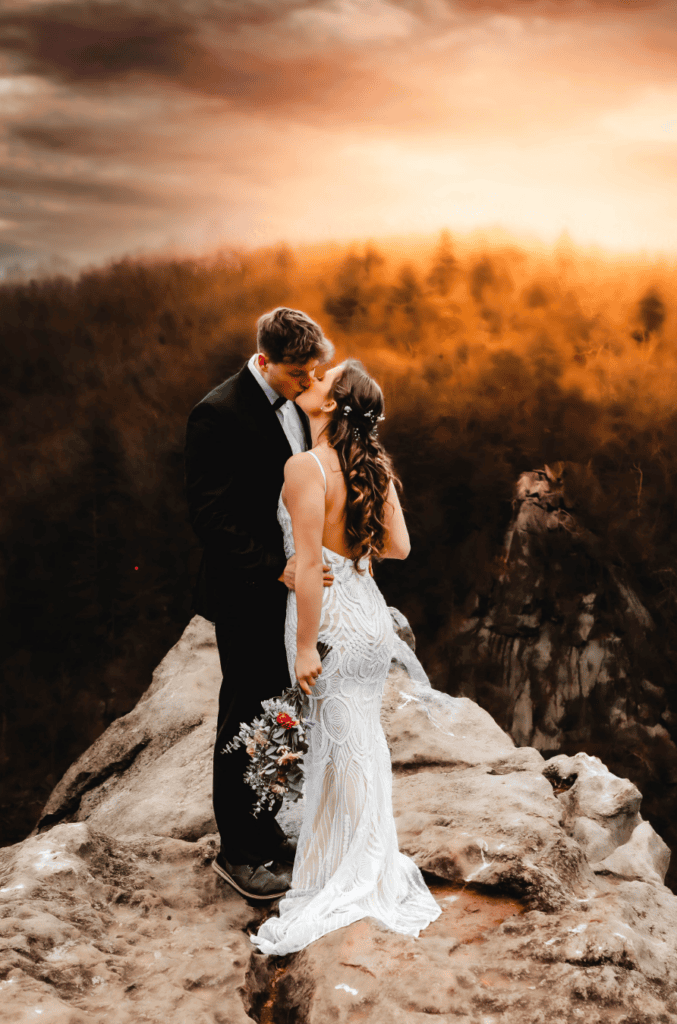 bride and groom sharing a romantic kiss on cliff edge at sunset